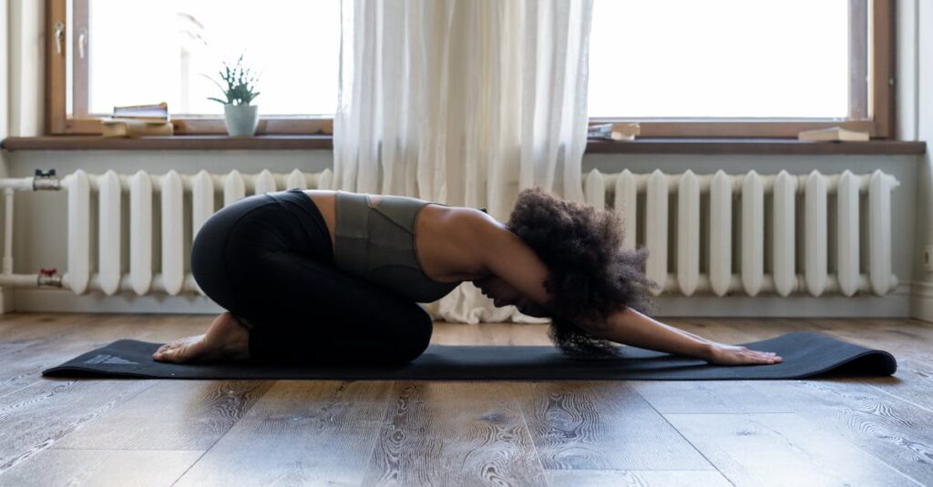 Woman practicing yoga at home on a mat in a cozy room. Embracing fitness and wellness indoors.